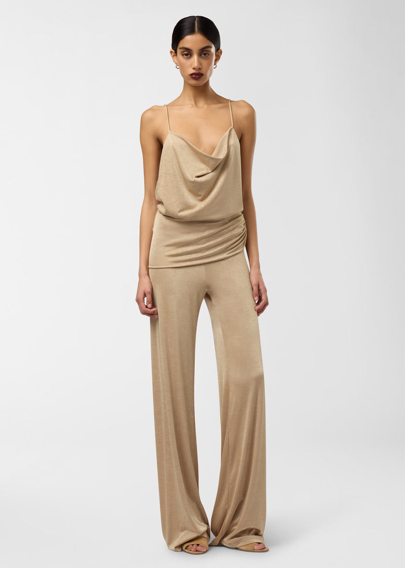 Frontal view: Carla Jumpsuit on standing model, showing a cowl neckline with thin straps, ruched waist drape, and loose wide-leg pants that sweep the floor, plain studio background.
