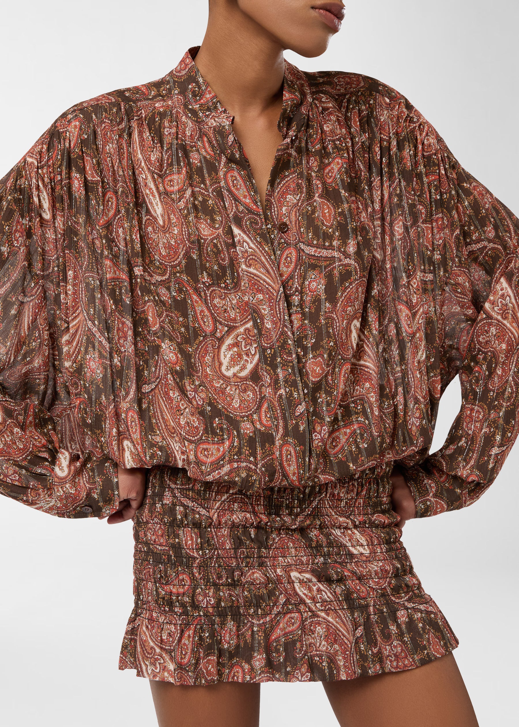 Frontal view: Rania Mini Dress worn by model, showing mandarin-collar shirt with pleated shoulders and button placket, and a smocked, frilled-hem skirt in brown paisley.