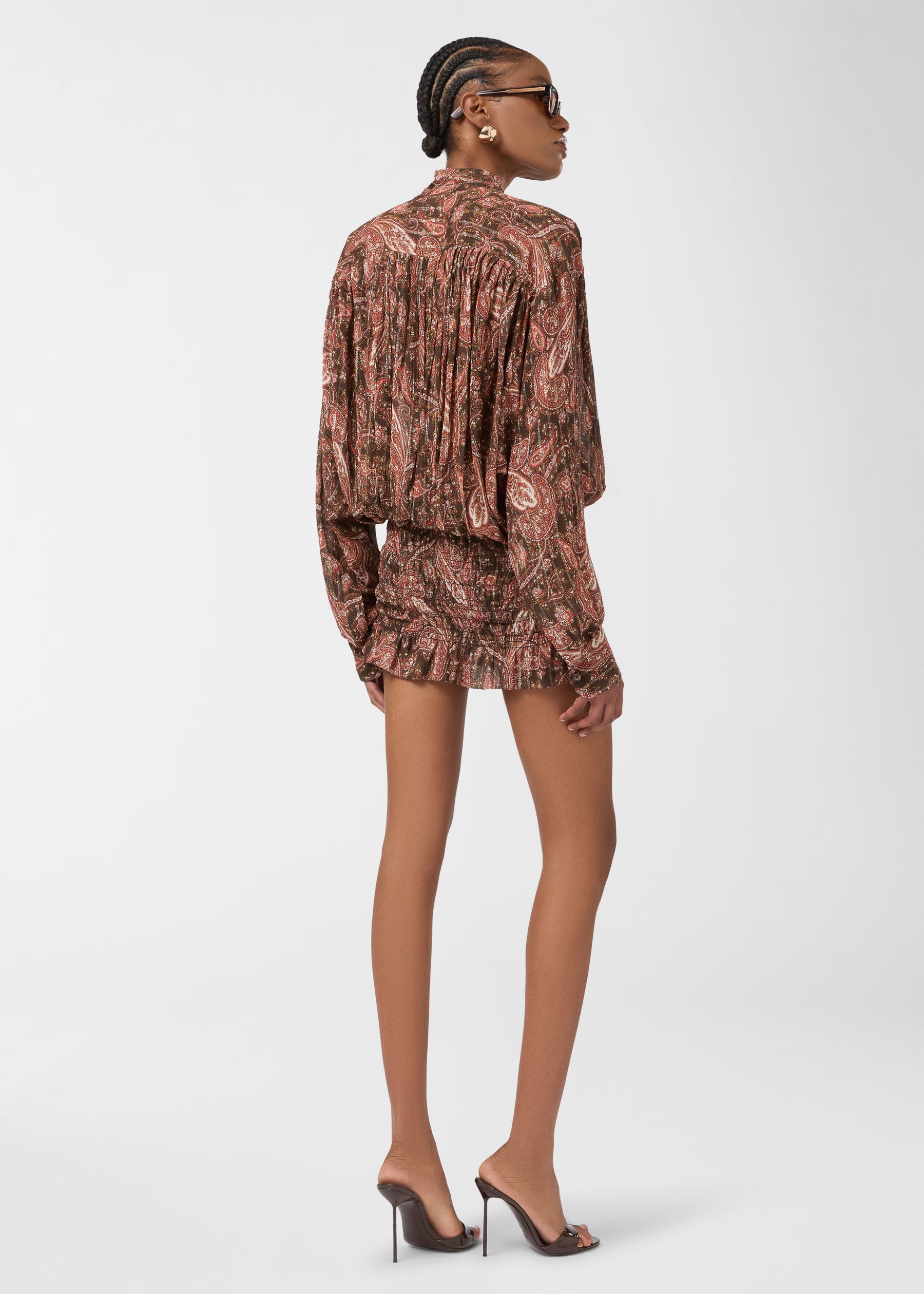 Rear view — Rania Mini Dress: model stands wearing paisley georgette dress, loose shirt top with mandarin collar and back pleats, smocked mini skirt with frilled hem.