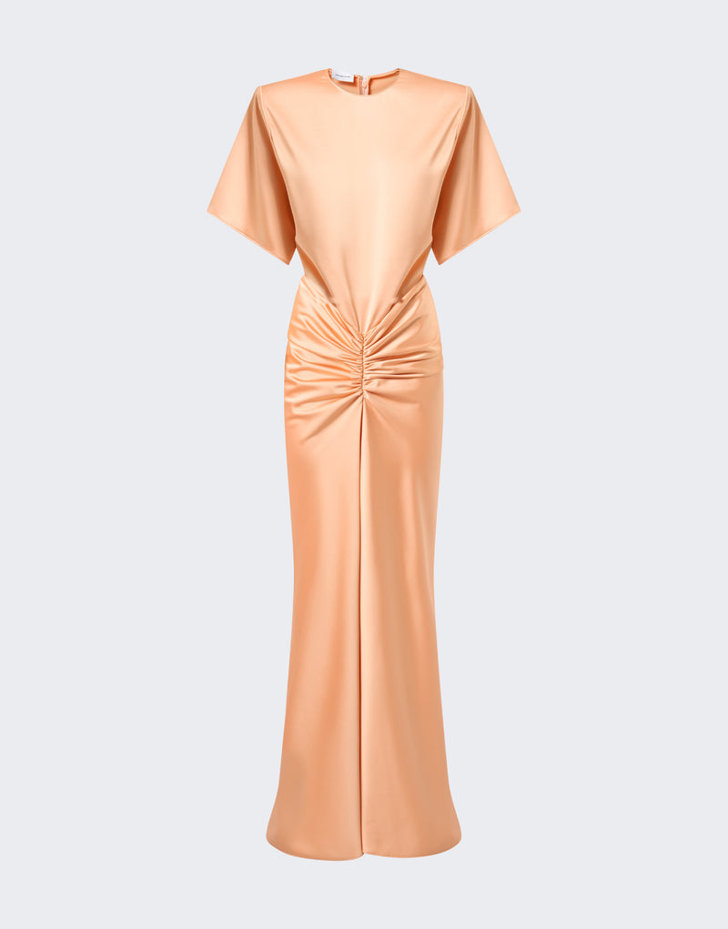 Frontal view: Iris Maxi Dress — peach liquid-satin gown on neutral background, showing shoulder-padded bodice with elbow-length sleeves, ruched waist gathering, and long fitted skirt.