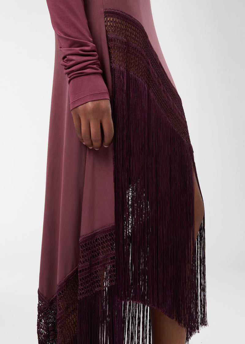 Detail view — Marisol Skirt displaying flowing rouge noir jersey with high-rise side panel, openwork weave and long straight fringe along an asymmetrical hem, model's hand at thigh.