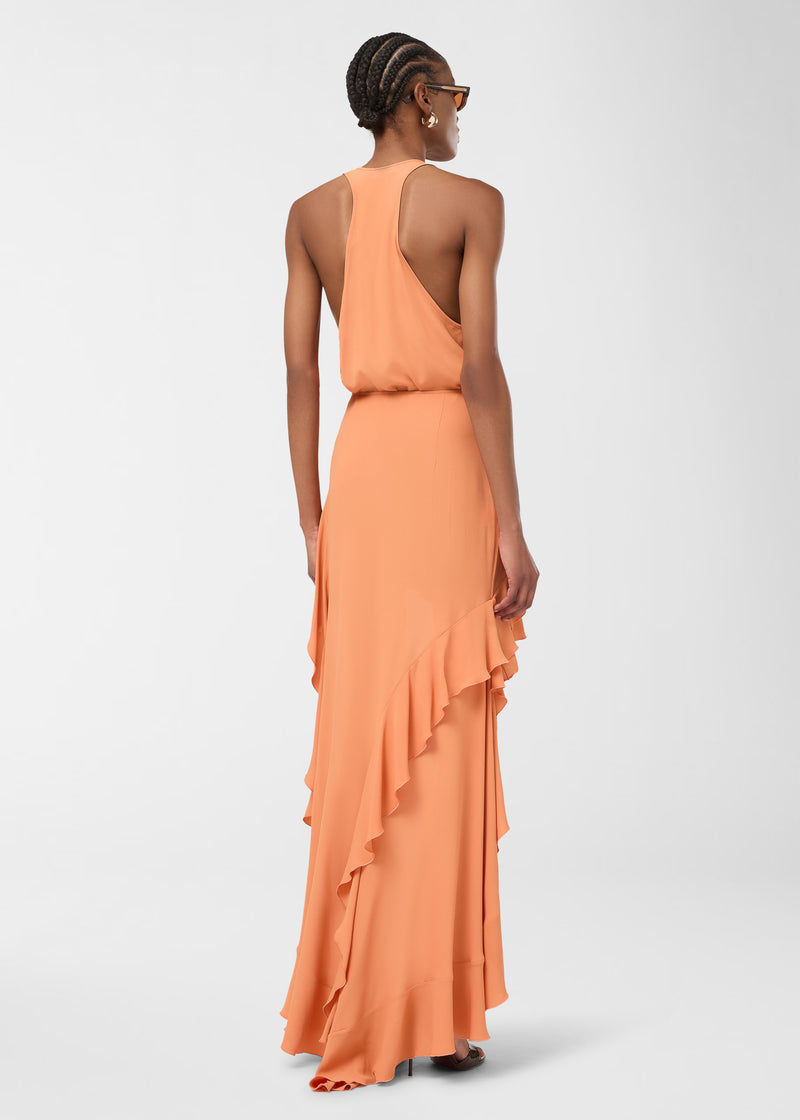 Rear view: Model stands wearing Camelia Maxi Skirt in tangerine, showing lightweight crepe de chine fabric and asymmetrical cascading ruffles flowing gracefully to the floor.