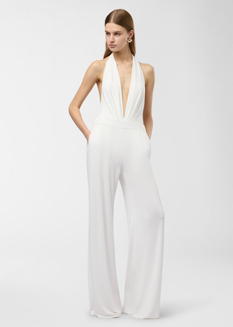 Frontal view — Model wearing Lana Pants stands with hands in side pockets, high-rise elastic waistband and wide off-white jersey floor-length legs against a studio backdrop.