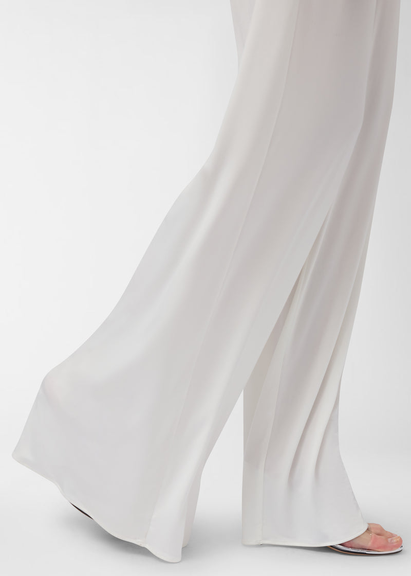 Frontal view: Lana Pants — off-white wide-leg pants draping and sweeping the floor as a model steps, showing high-rise silhouette and concealed side-slit pockets in studio.