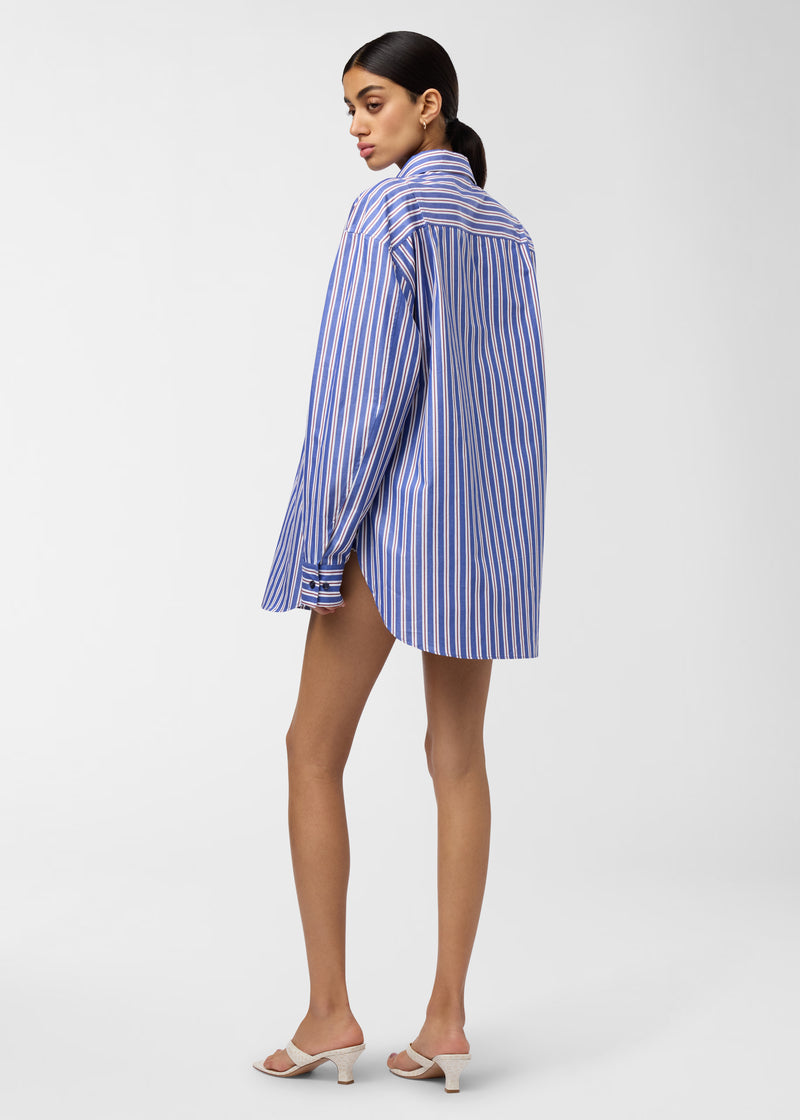 Rear view: New Georgiana Shirt on model, displaying oversized blue-and-rouge noir maxi-striped cotton, back yoke and curved hem, long sleeves, posed against plain studio background.