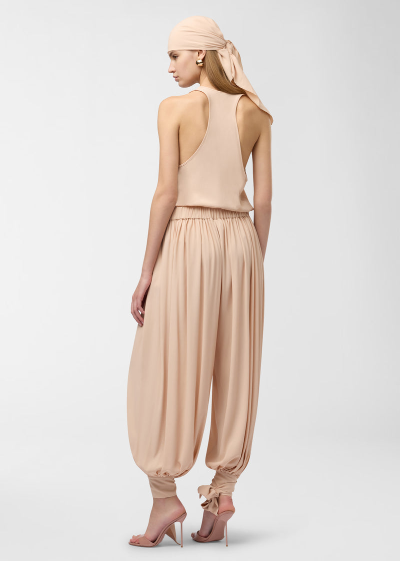 Rear view: Model wearing Pura Top displays scooped neckline and racerback as lightweight peach crepe drapes over the body, styled with matching headscarf against a plain studio background.