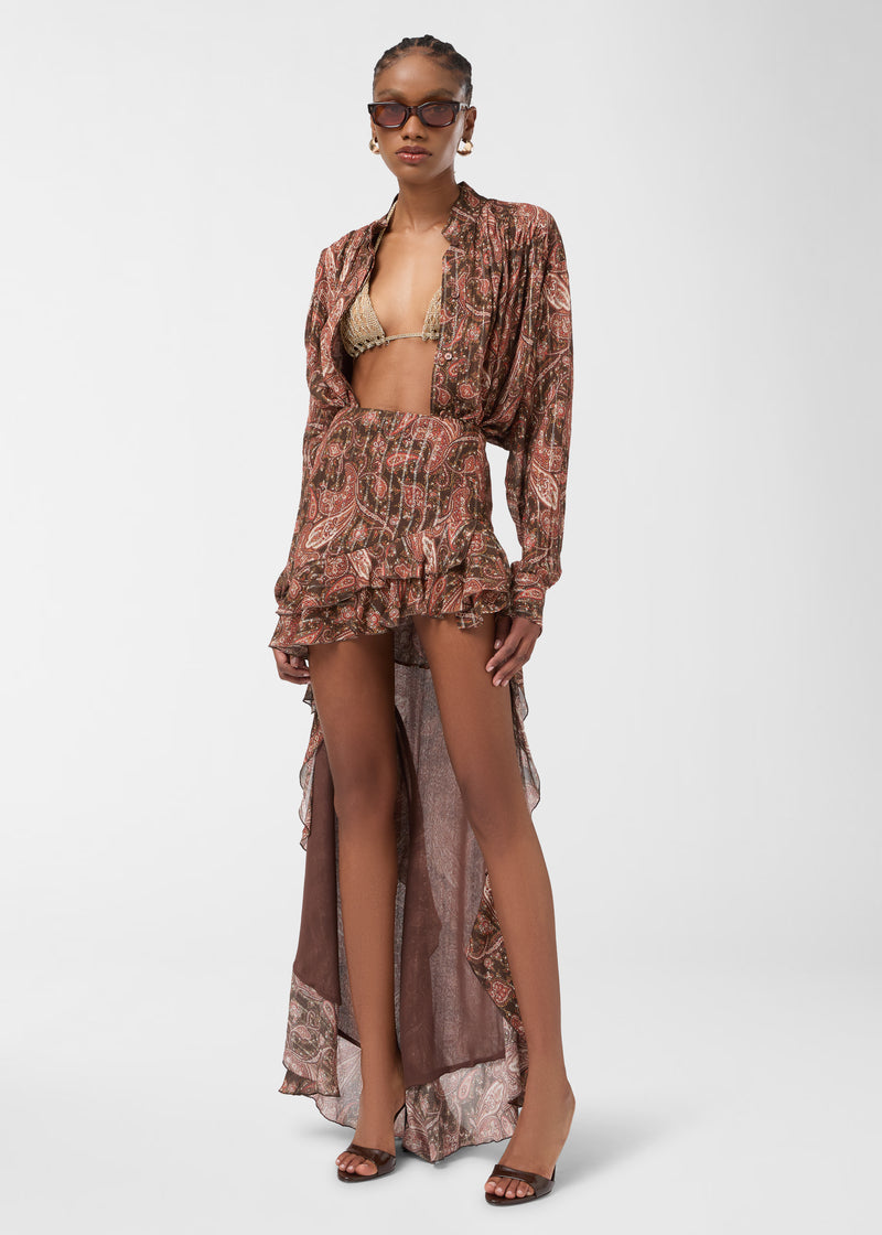 Frontal view: Rania Shirt displayed on model, worn unbuttoned over a bikini top, photographed against a plain studio background, showing paisley georgette, mandarin collar and pleated details.
