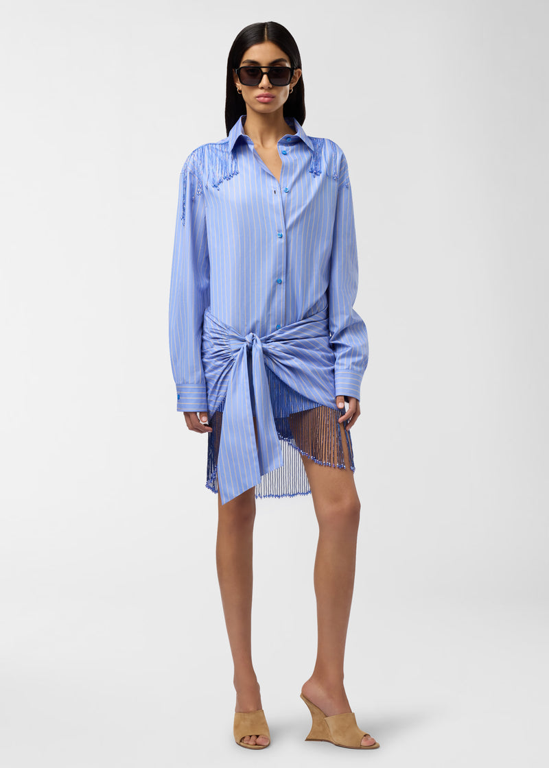 Frontal view — Dolly Pareo: light blue maxi-striped cotton wrap tied at waist with draped pleats and knotted front, bejeweled fringe hem, modeled on standing woman.