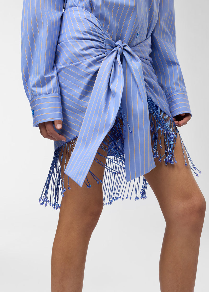 Frontal view — Dolly Pareo wrapped and knotted at the waist over a matching striped shirt, with draped pleating and bejeweled fringe cascading over the thighs.